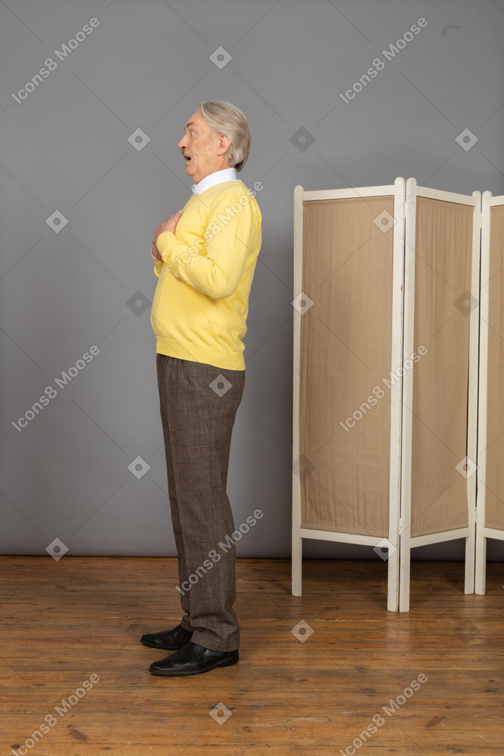 Side view of an astonished old man touching chest