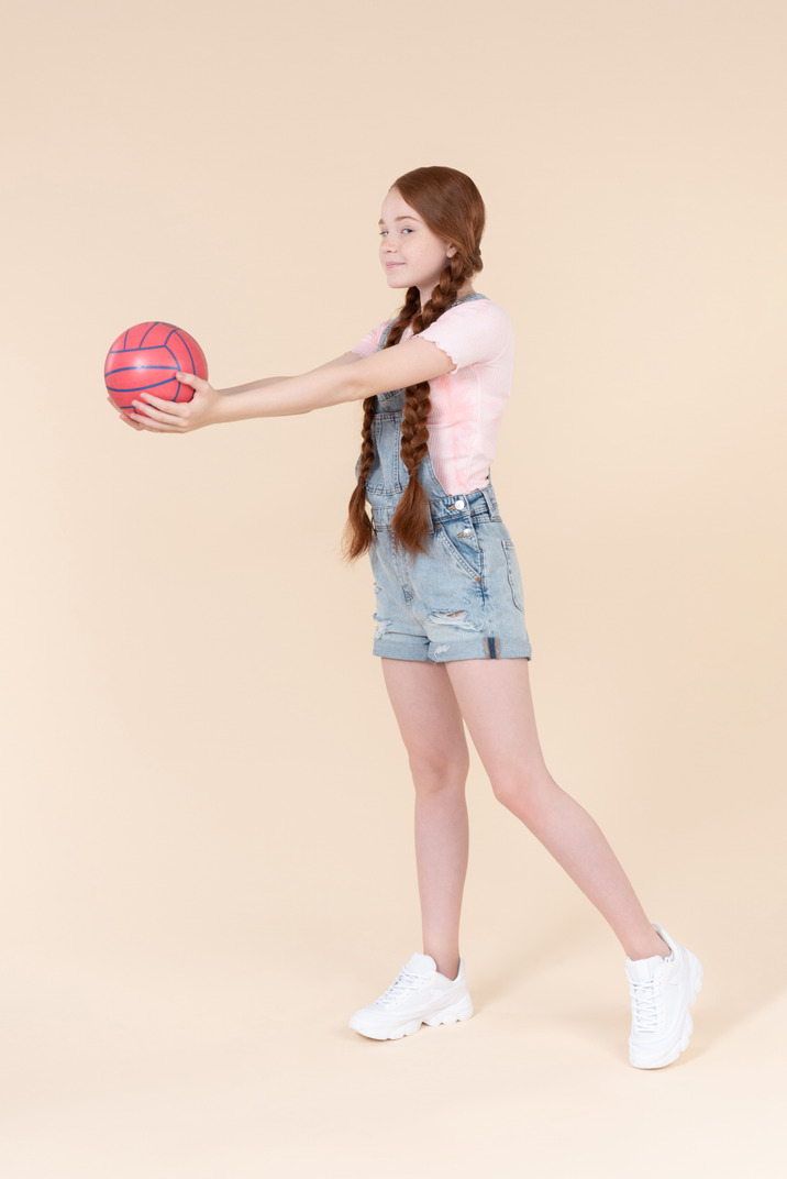 Teenage girl standing half sideways and holding ball