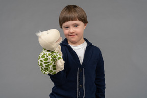 Portrait of a little boy holding a tortoise puppet