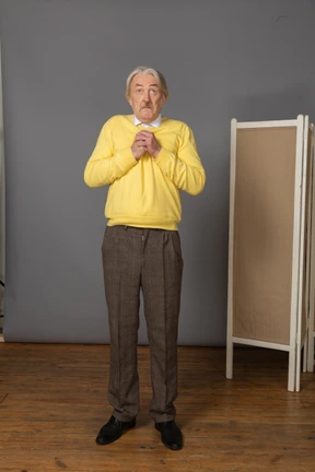 Front view of a surprised old man holding hands together