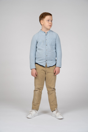 Vista frontal del niño con ropa informal mirando a un lado