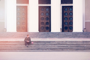 젊은 남자는 건물 앞 계단에 앉아