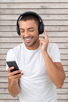 A man wearing headphones and listening to music on his phone