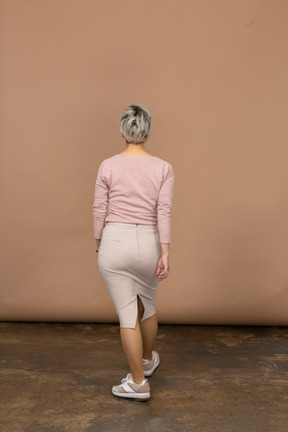 歩くカジュアルな服を着た女性の背面図