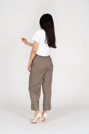 Three-quarter back view of a young woman in breeches and white t-shirt showing a size of something