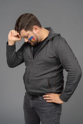Three-quarter view of a puzzled male football fan touching head