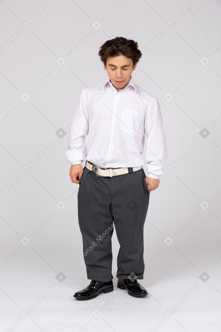 Young man in shirt and trousers looking down