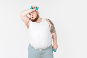 Tired big guy in sportswear lifting hand weights