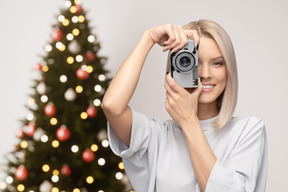 クリスマスツリーの前で写真を作る若い女性