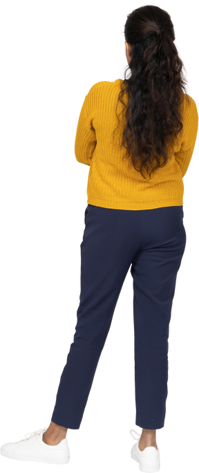 Vista posteriore di una ragazza in abiti casual in piedi con le braccia incrociate
