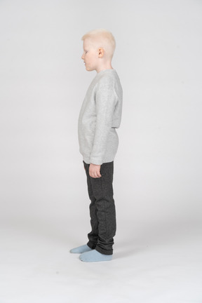 Vista lateral de un niño chico en ropa casual mirando hacia abajo