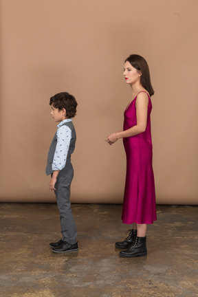 Young woman in dress standing and holding her hand with boy