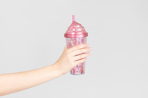 Femme main tenant une tasse en plastique rose