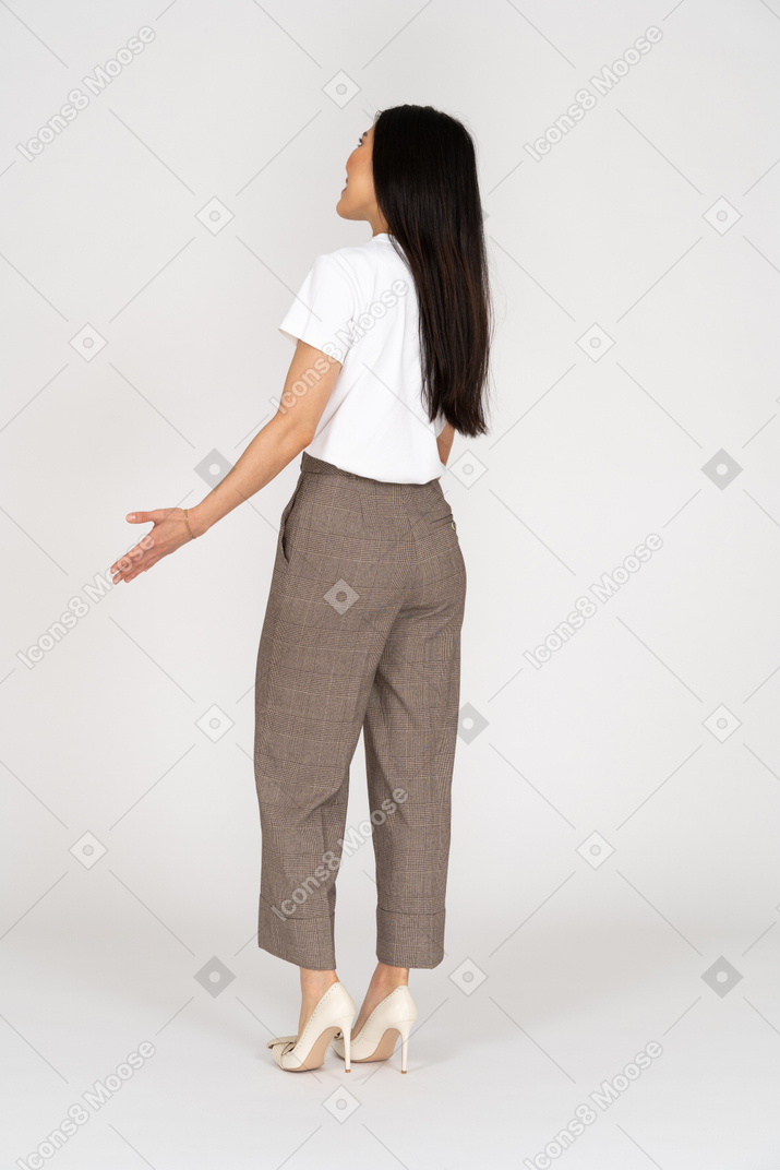 Vista posterior de tres cuartos de una joven sonriente en pantalones y camiseta