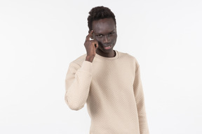 Un joven negro en un suéter gris de pie solo sobre el fondo blanco.