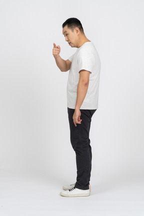 Side view of a man in casual clothes pointing at something and looking aside