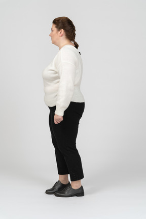 프로필에 서있는 흰색 스웨터에 플러스 크기 여자