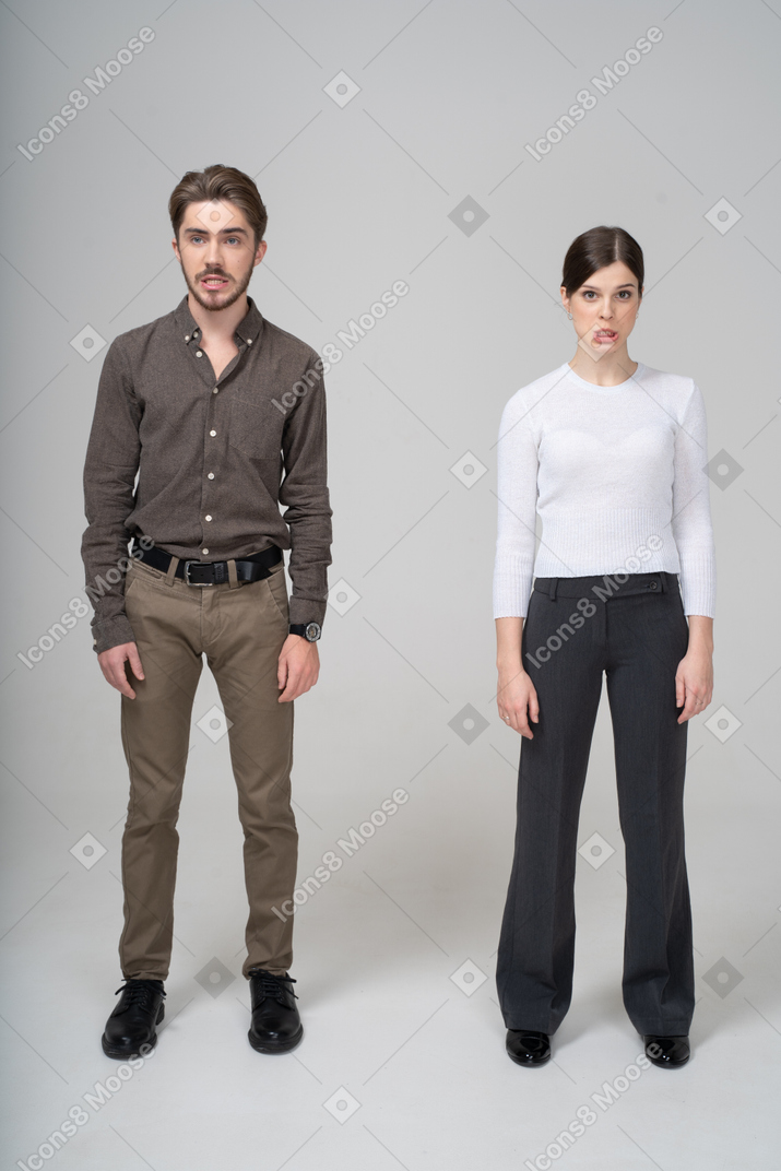 Front view of a grimacing young couple in office clothing