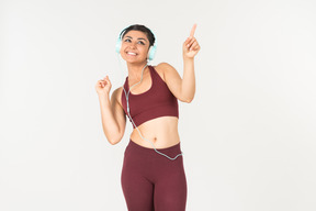 Rire jeune femme indienne en sporstwear, écouter de la musique au casque