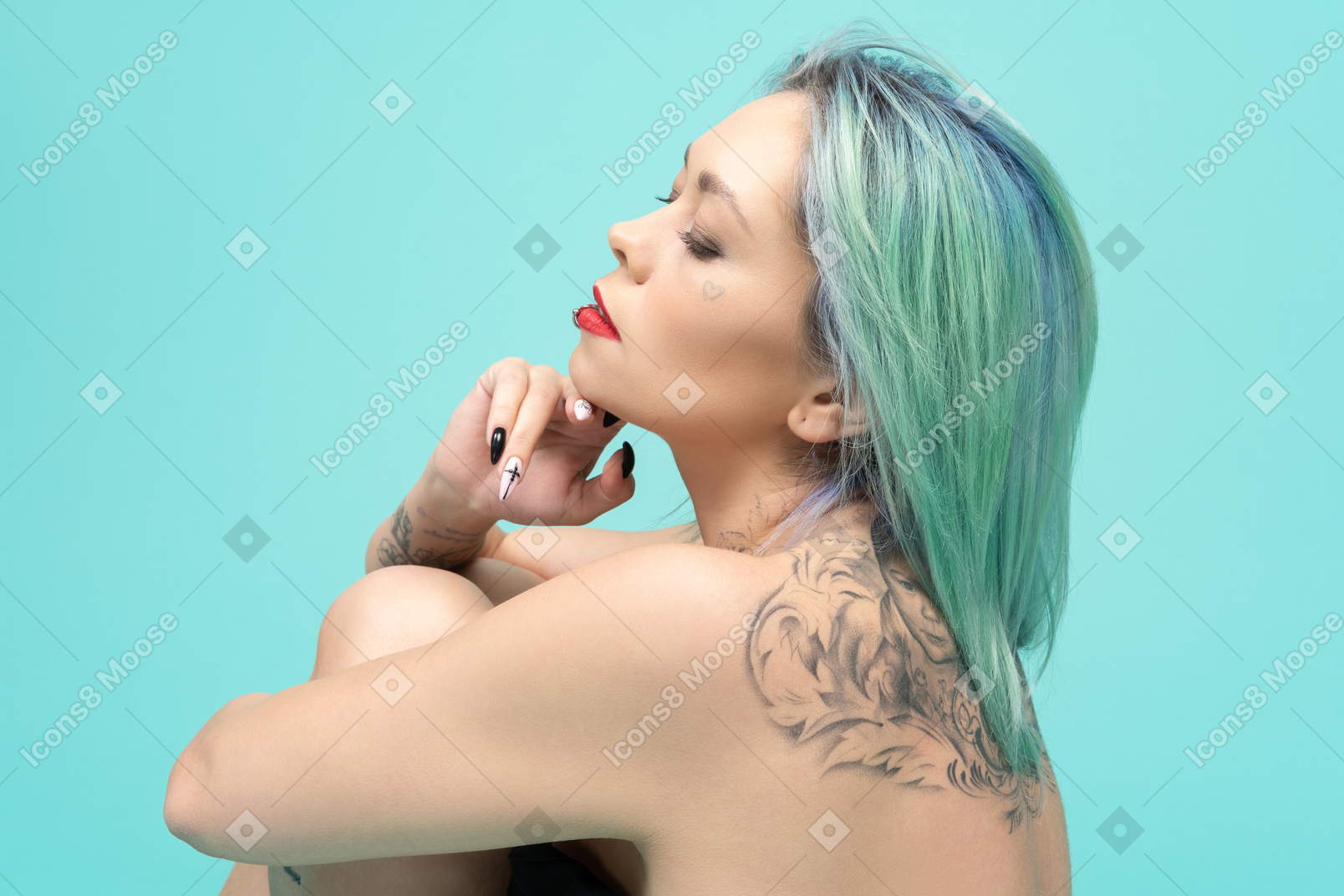 Close-up de una mujer caucásica tatuada sobre fondo turquesa