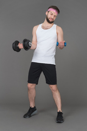 Man trying heavy and light dumbbell