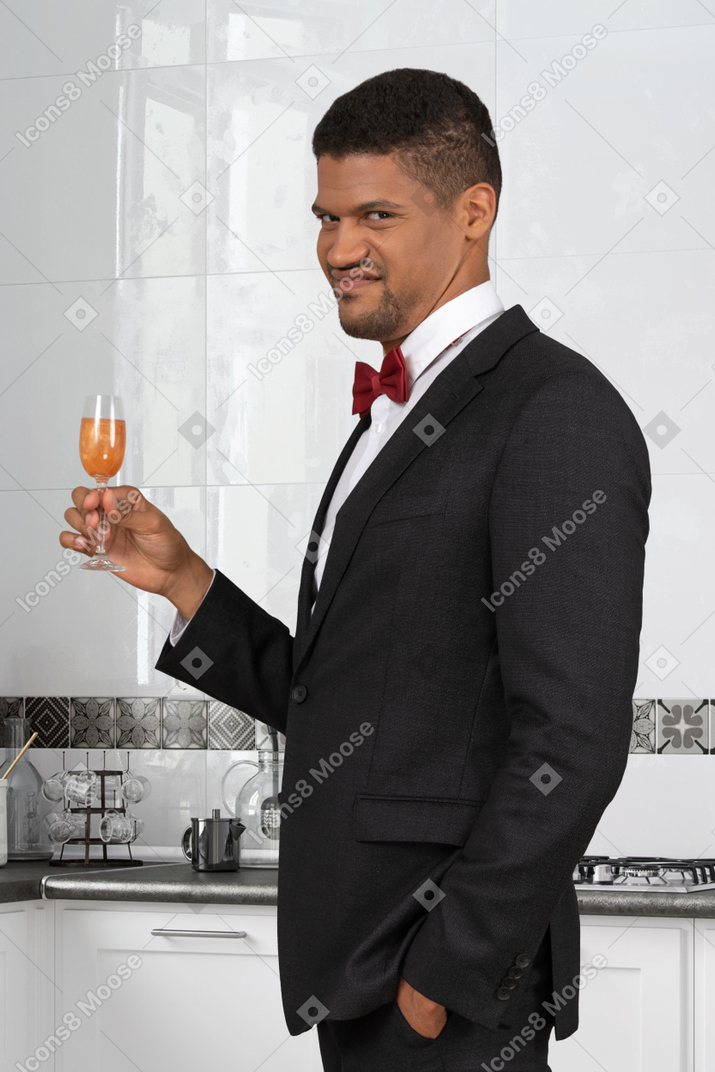 A wincing man in a suit holding a drink