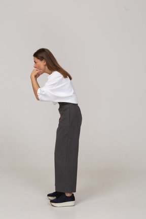 Vista lateral de una señorita silbando en ropa de oficina inclinado hacia adelante