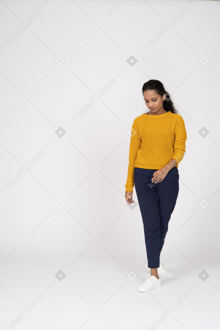 Front view of a girl in casual clothes walking and looking down