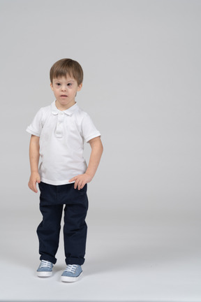 Front view of little boy standing with arms at side
