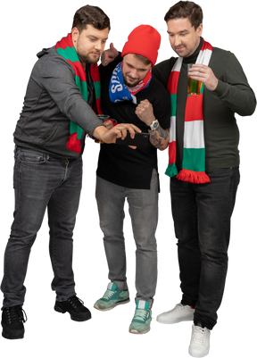 Vista frontal de tres aficionados al fútbol masculino tomando selfie