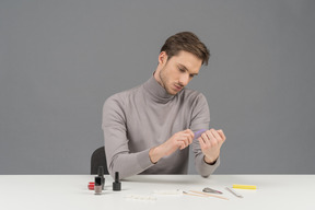 A young man arranging his nails