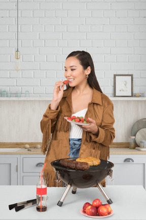 A woman standing in a kitchen holding a plate of food