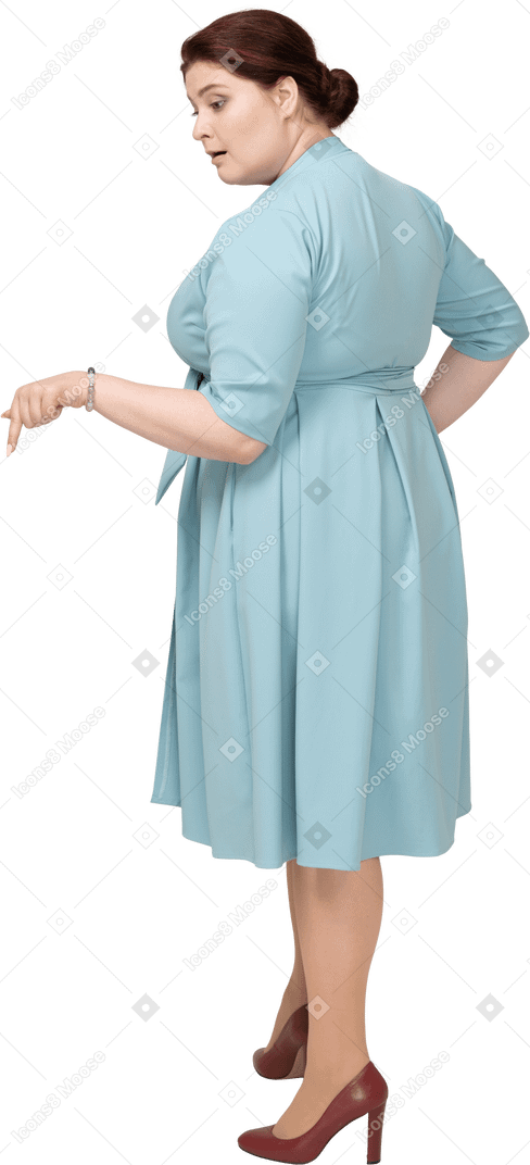 Vue latérale d'une femme en robe bleue pointant vers le bas avec un doigt