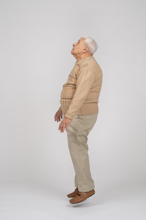 Side view of an old man in casual clothes jumping