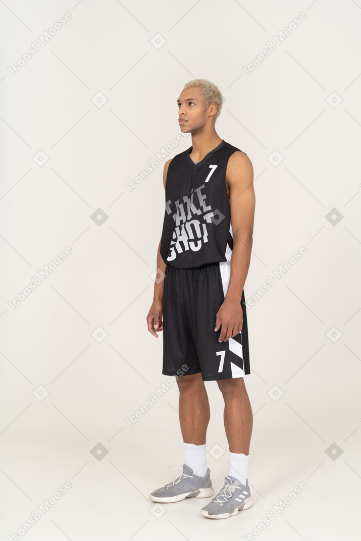 Three-quarter view of a young male basketball player standing still