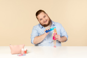 Big man holding hair brush and barbie doll
