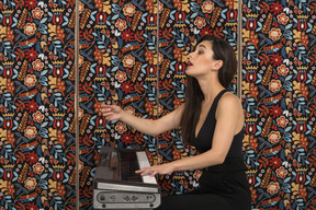 Giovane donna che punta lateralmente con una mano mentre suona il pianoforte