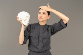Vista frontale di una giovane donna in tuta che tiene in mano un teschio di gesso