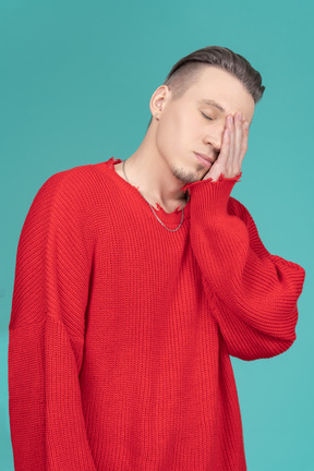 赤いセーターで眠そうな若い男