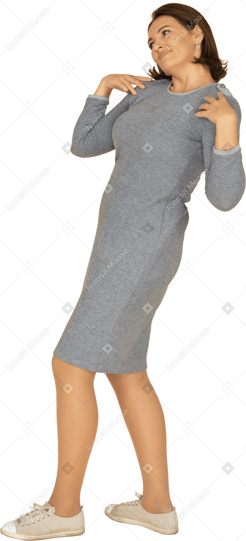 Vista laterale di una donna in abito grigio in piedi con le mani sulle spalle