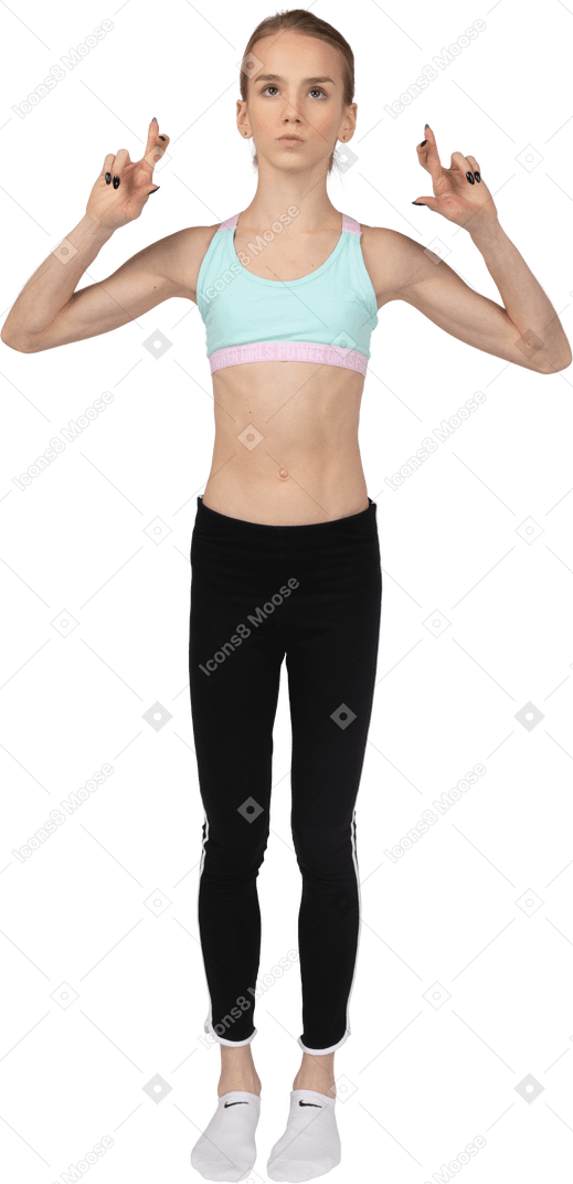 Vista frontal de uma adolescente em roupas esportivas cruzando os dedos