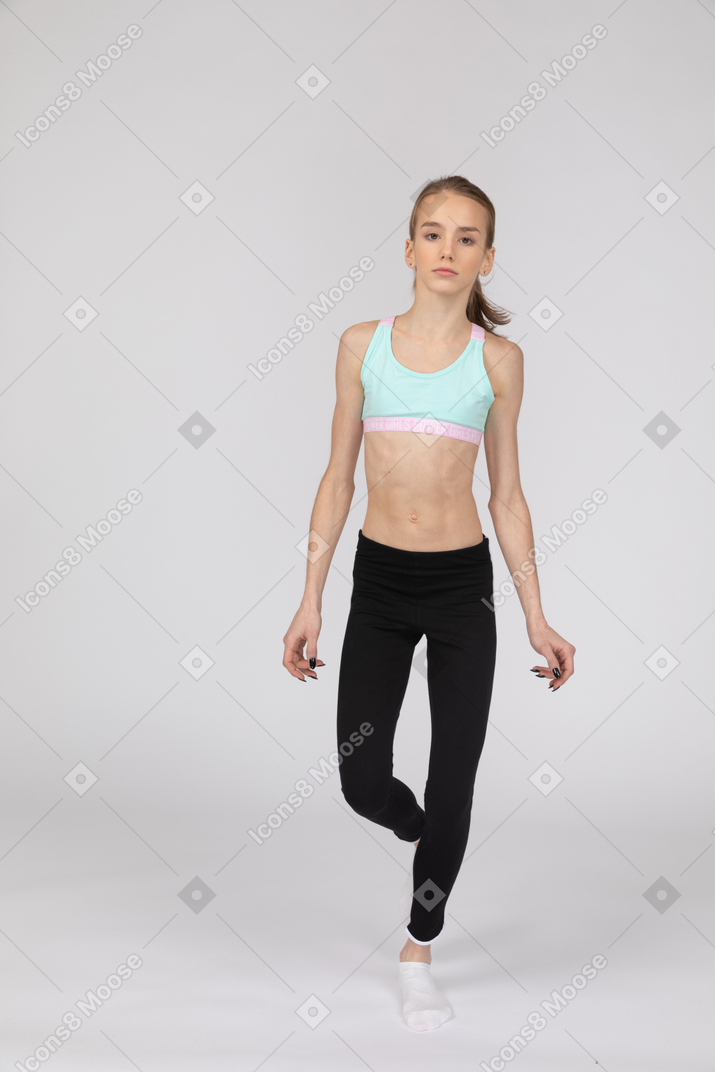 Front view of a teen girl in sportswear looking at camera stepping forward