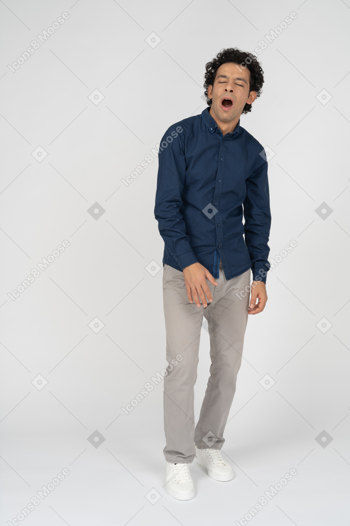 Front view of a man in casual clothes yawning