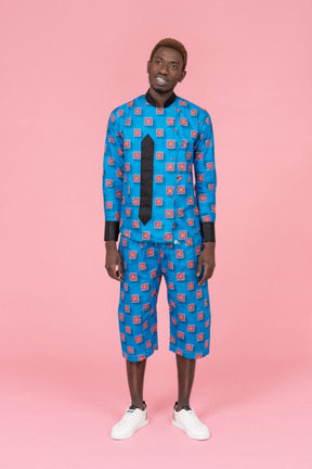 Black man in blue pajamas standing on pink background