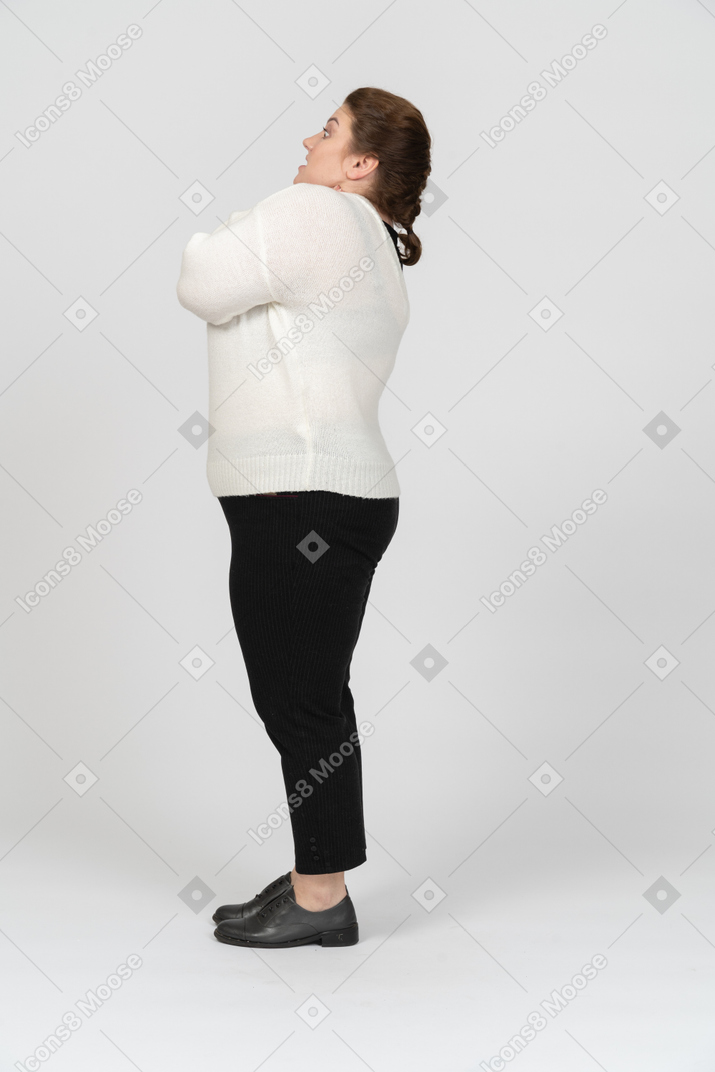 Vista lateral de uma mulher gordinha impressionada com um suéter branco