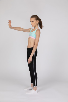 Una adolescente en ropa deportiva extendiendo su brazo.
