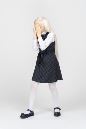 Schoolgirl covering her face with hands
