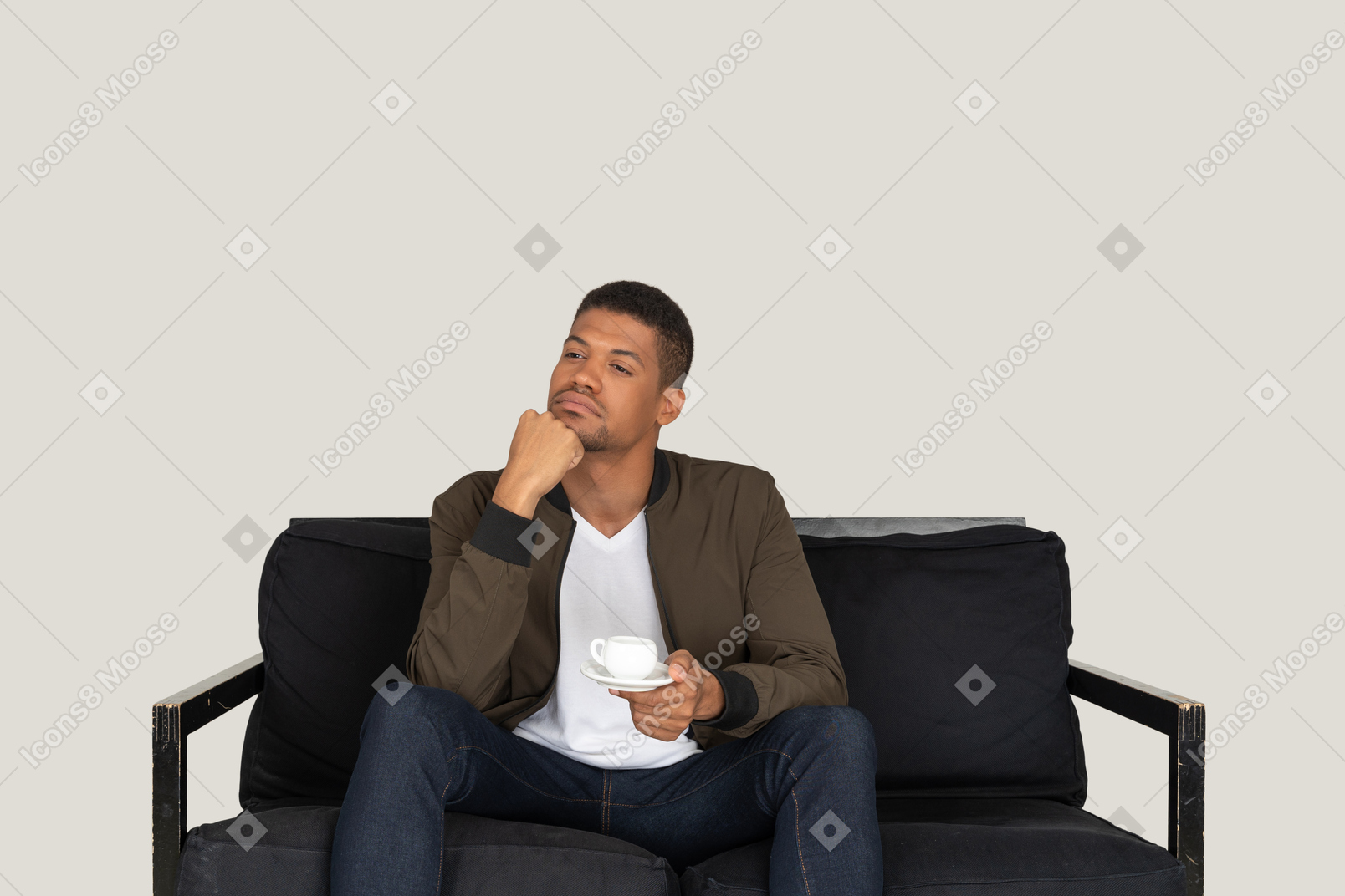 一个体贴的年轻男子坐在沙发上，端着一杯咖啡的前视图