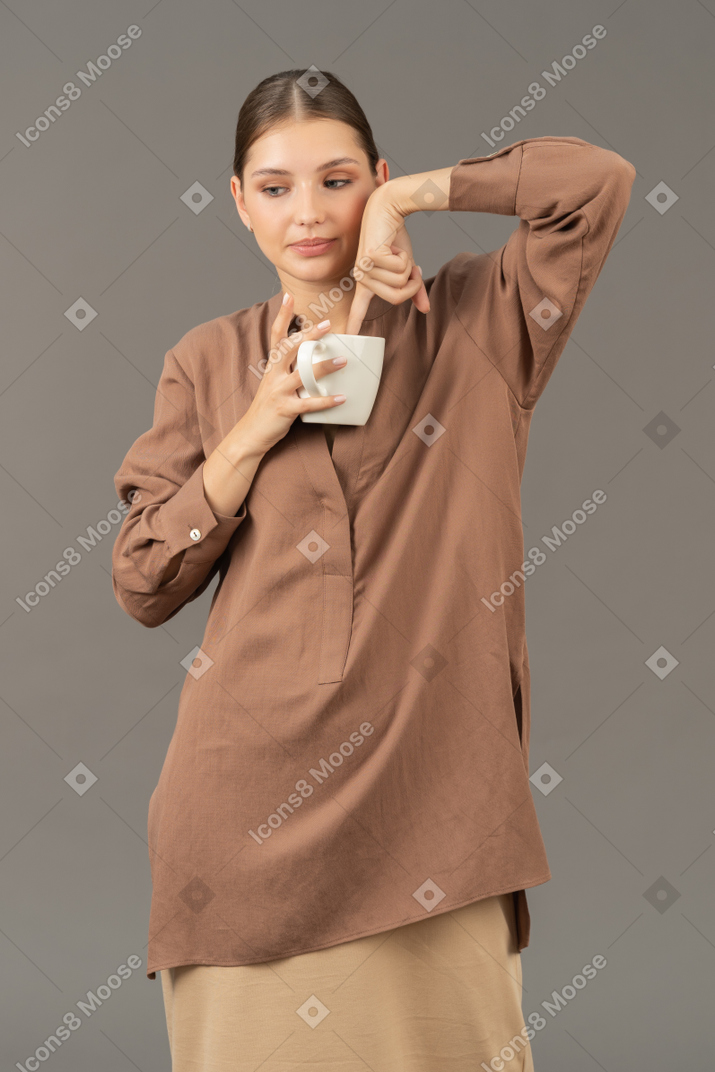 커피 컵에 손가락으로 옆을 바라보는 젊은 여성