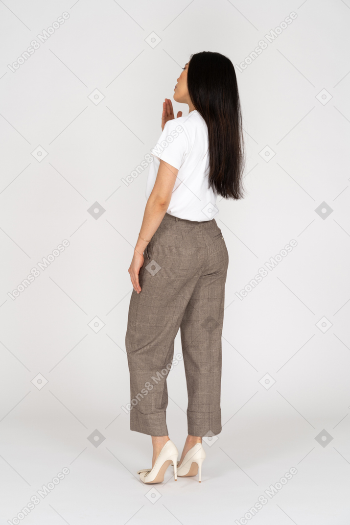 Three-quarter back view of a young lady in breeches and t-shirt raising hand